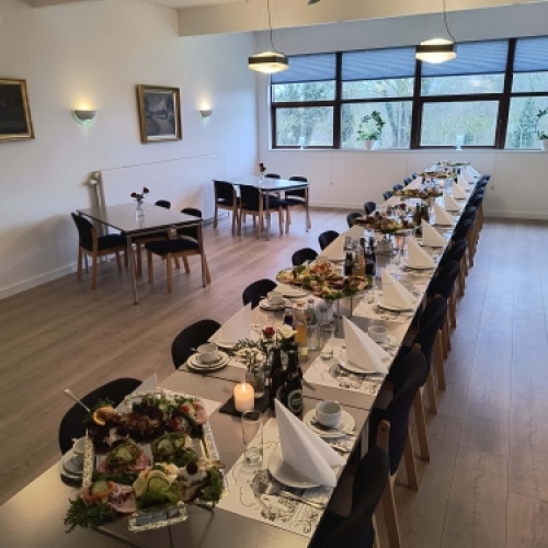 Selskabslokale opdækket til festligt arrangement med langbord og bordpynt