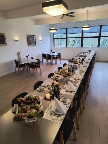 Selskabslokale opdækket til festligt arrangement med langbord og bordpynt